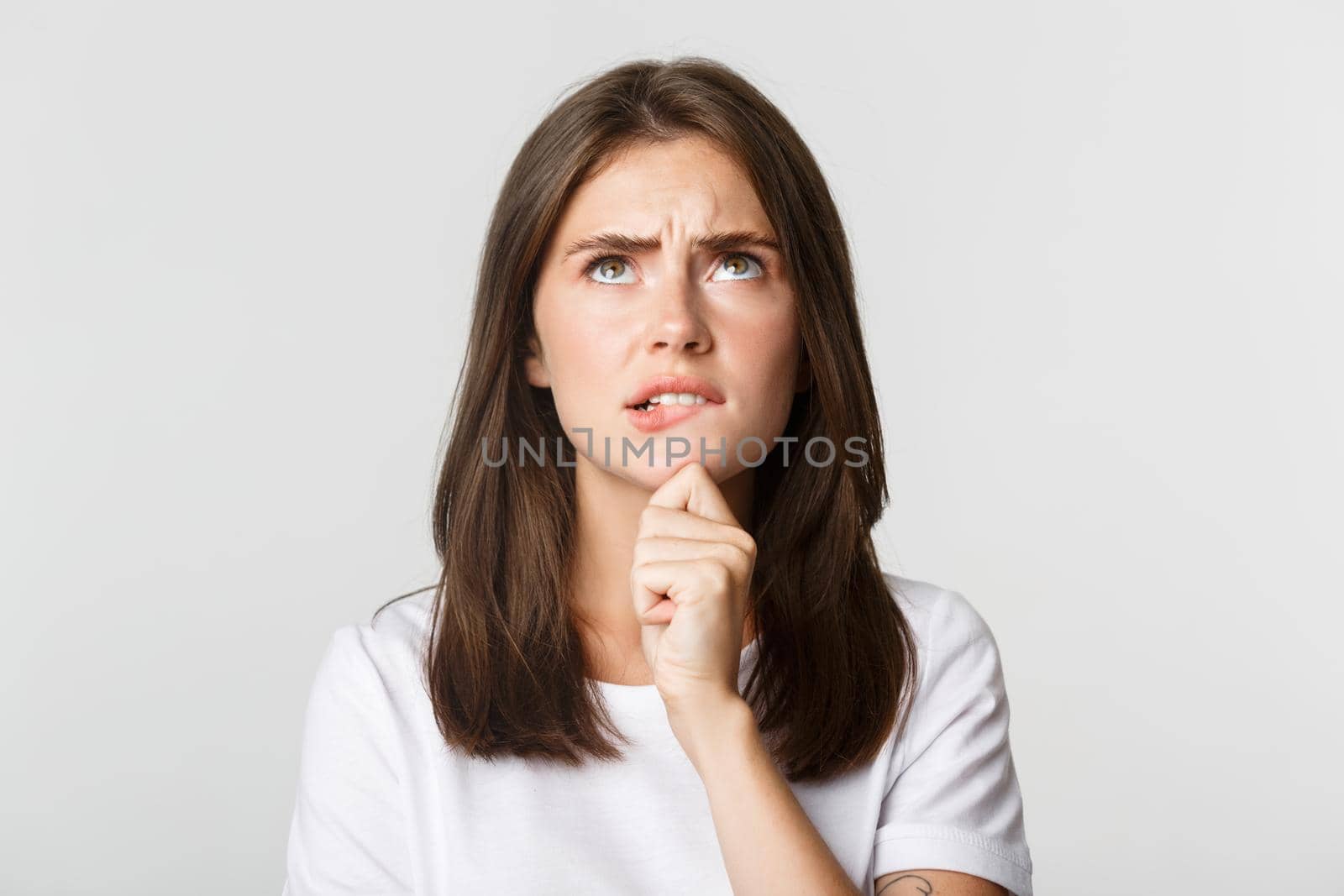 Close-up of puzzled cute thoughtful girl looking up and thinking, standing white background and pondering decision.