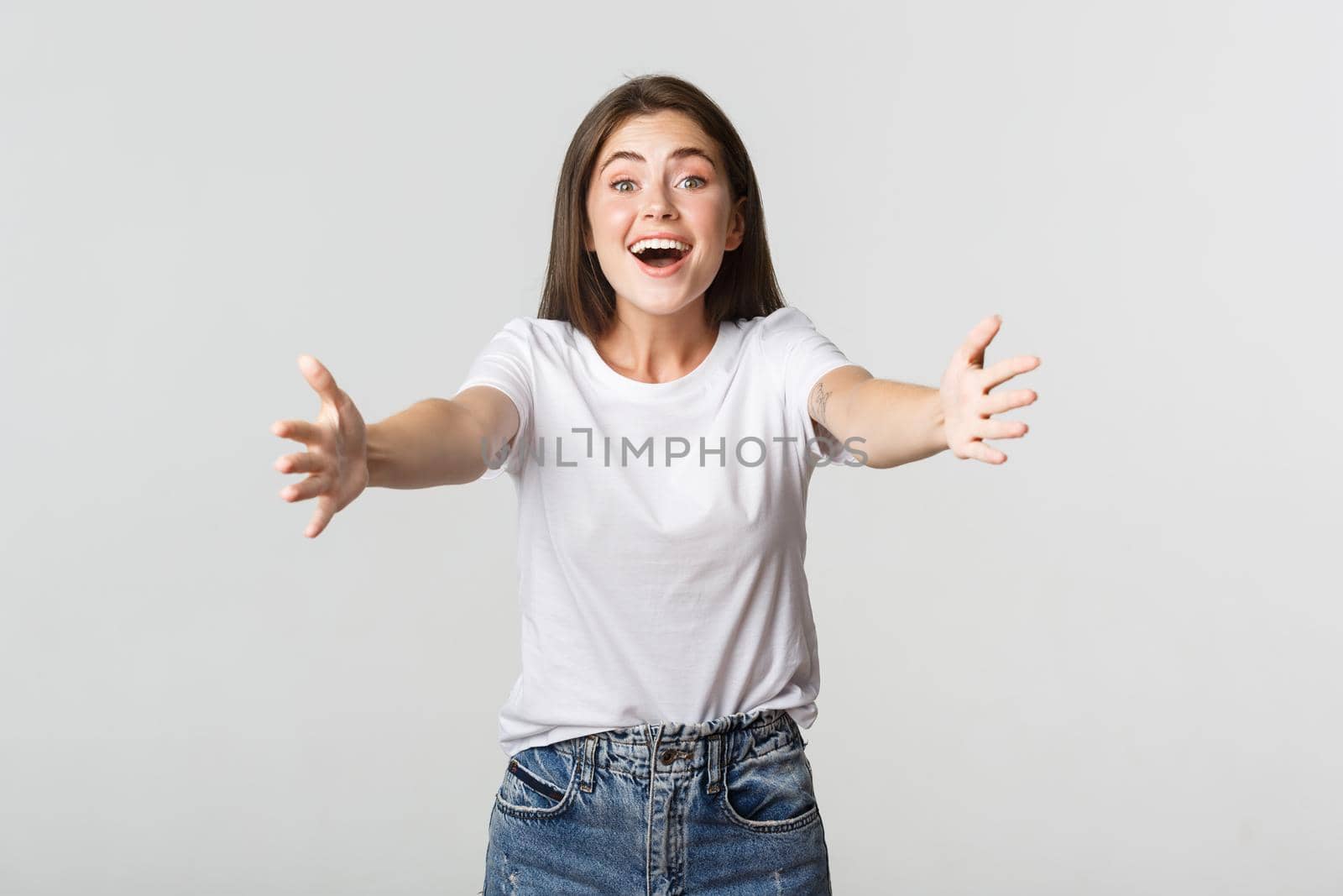 Excited beautiful girl extend hands forward, reaching for hug and smiling.