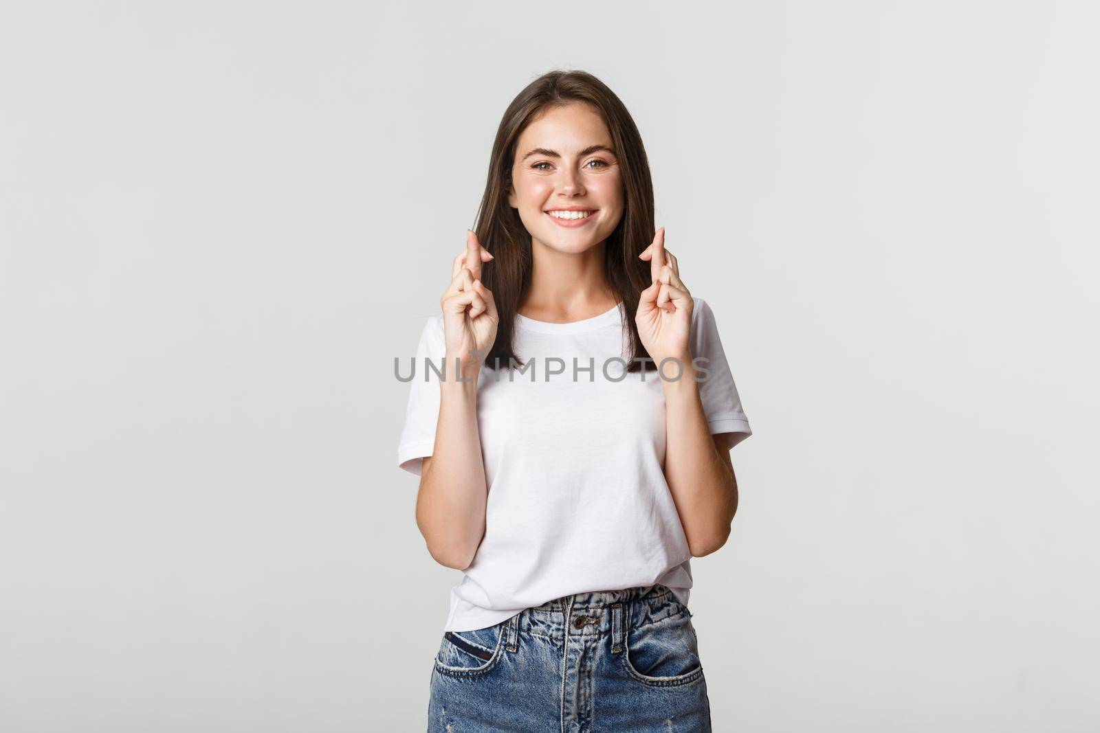 Hopeful smiling girl cross fingers good luck, making wish or praying.