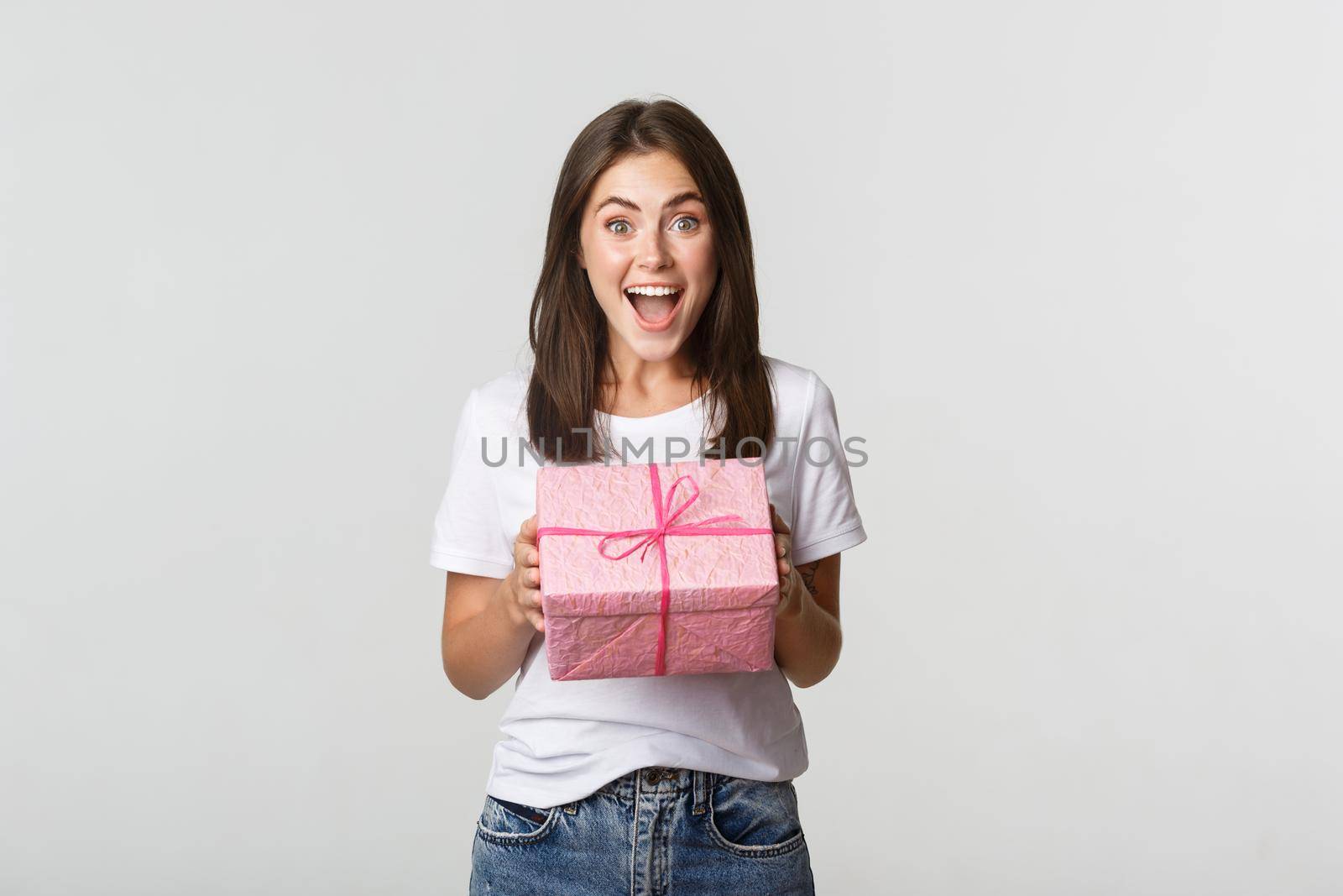 Surprised happy birthday girl receiving wrapped gift, white background.