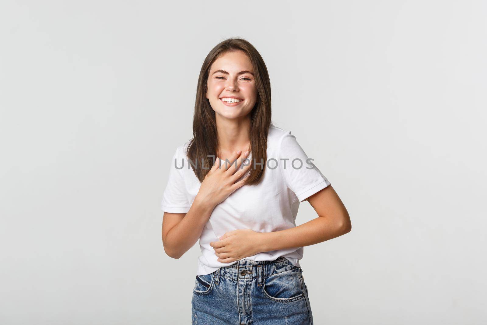 Happy beautiful girl laughing and touching chest, looking thankful.