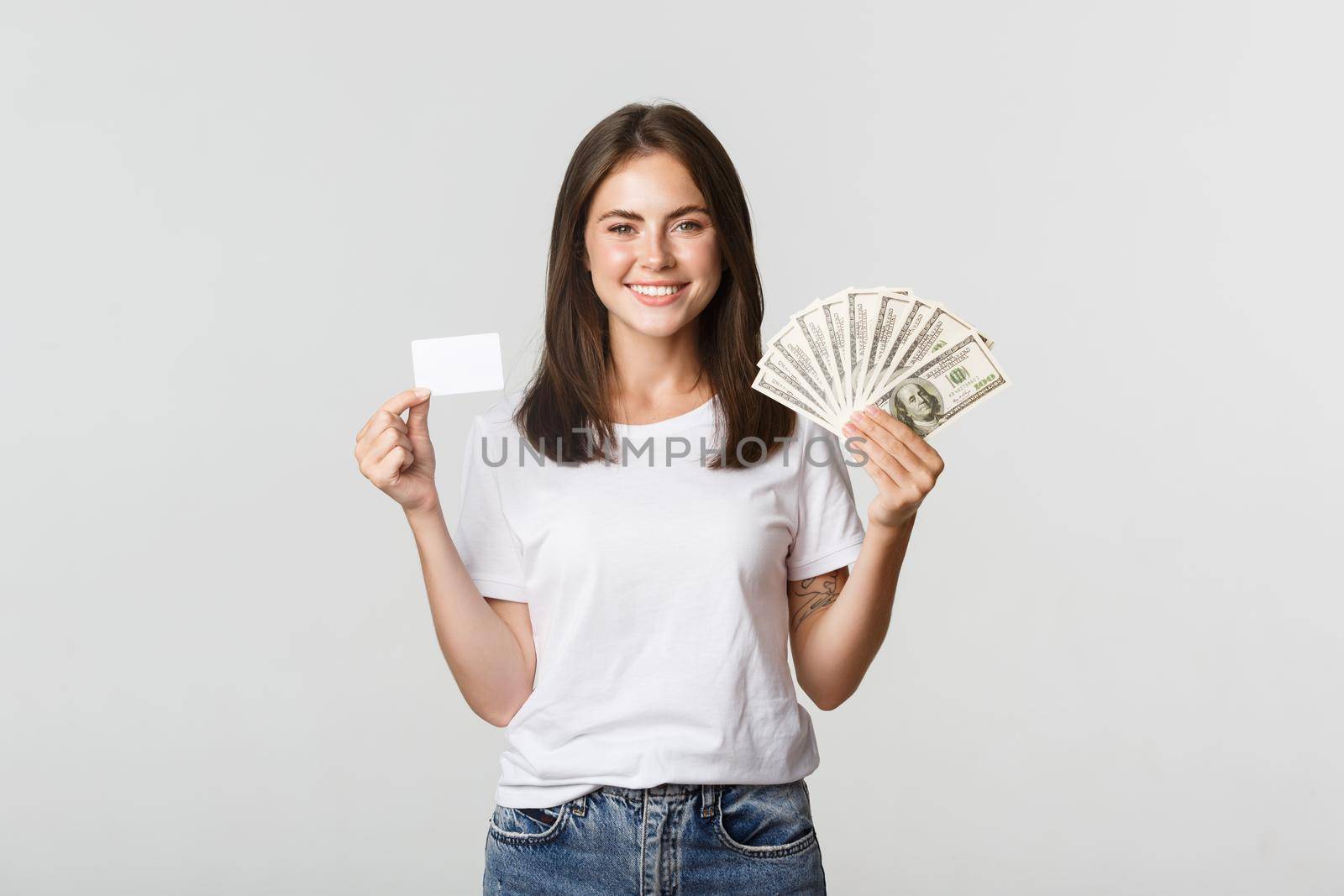 Portrait of excited smiling girl holding money and credit card, white background.