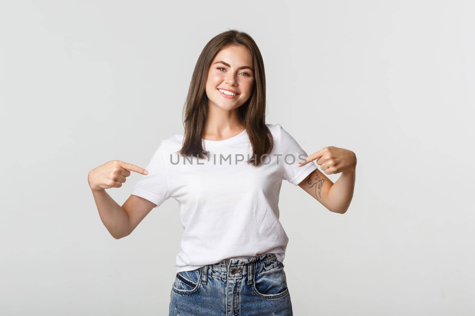 Attractive smiling brunette girl pointing at your logo, showing banner on center.