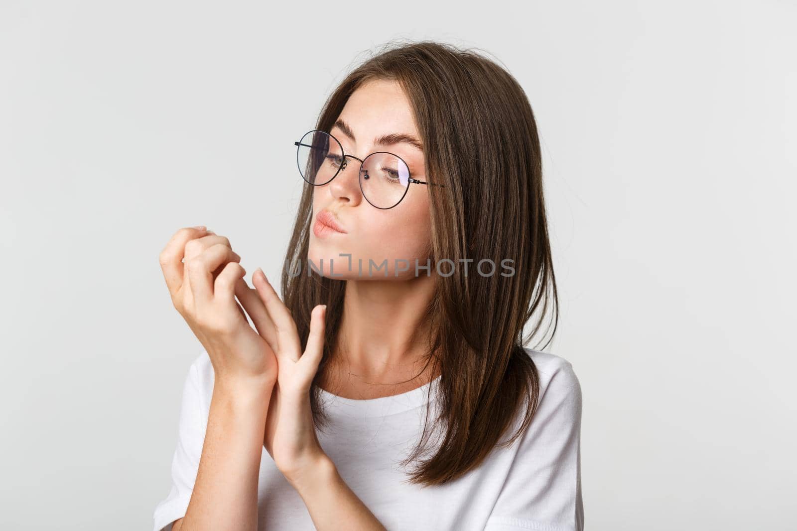 Close-up of attractive young brunette woman in glasses looking at fingernails after beauty salon.