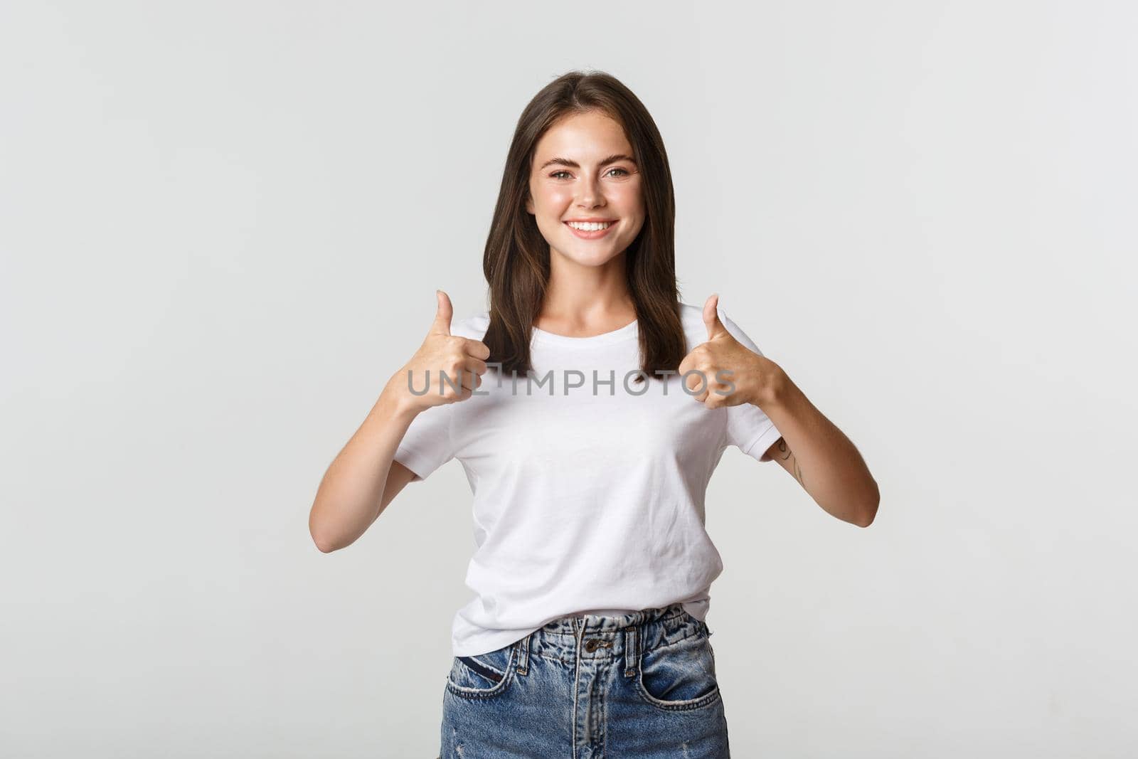Happy satisfied young woman smiling, showing thumbs-up in approval, like something.
