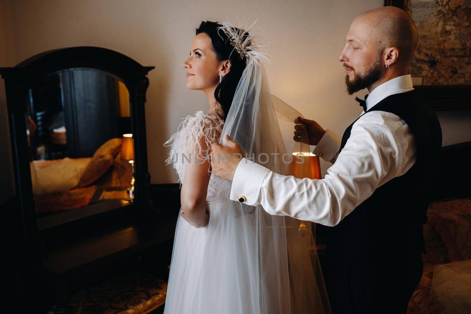 Morning of the bride. The groom helps to dress the bride in a wedding dress.