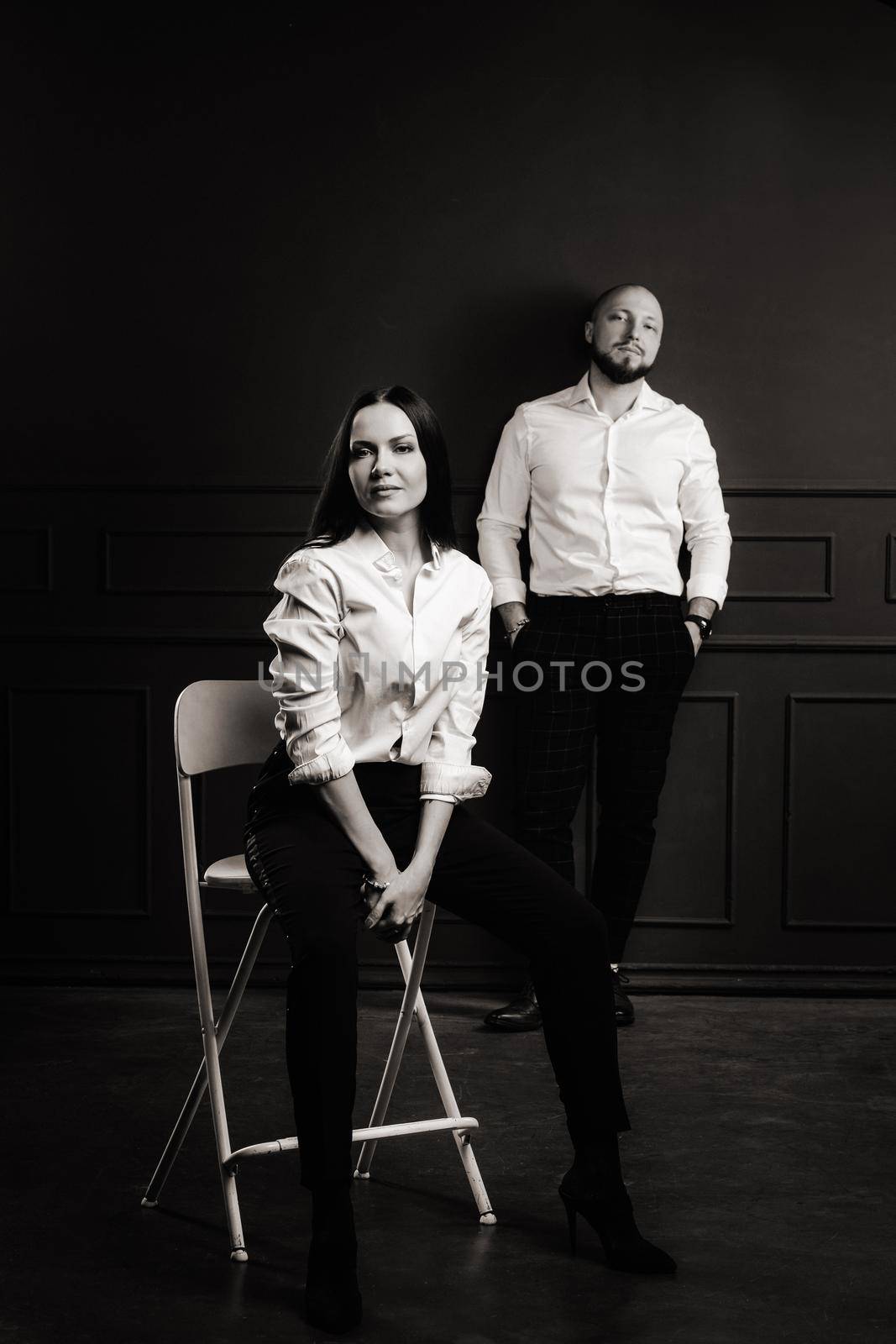 A man and a woman in white shirts on a black background.A couple in love in the studio interior.black and white photo.