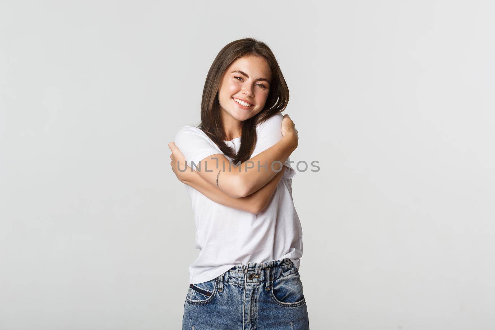 Attractive smiling tender woman hugging herself.