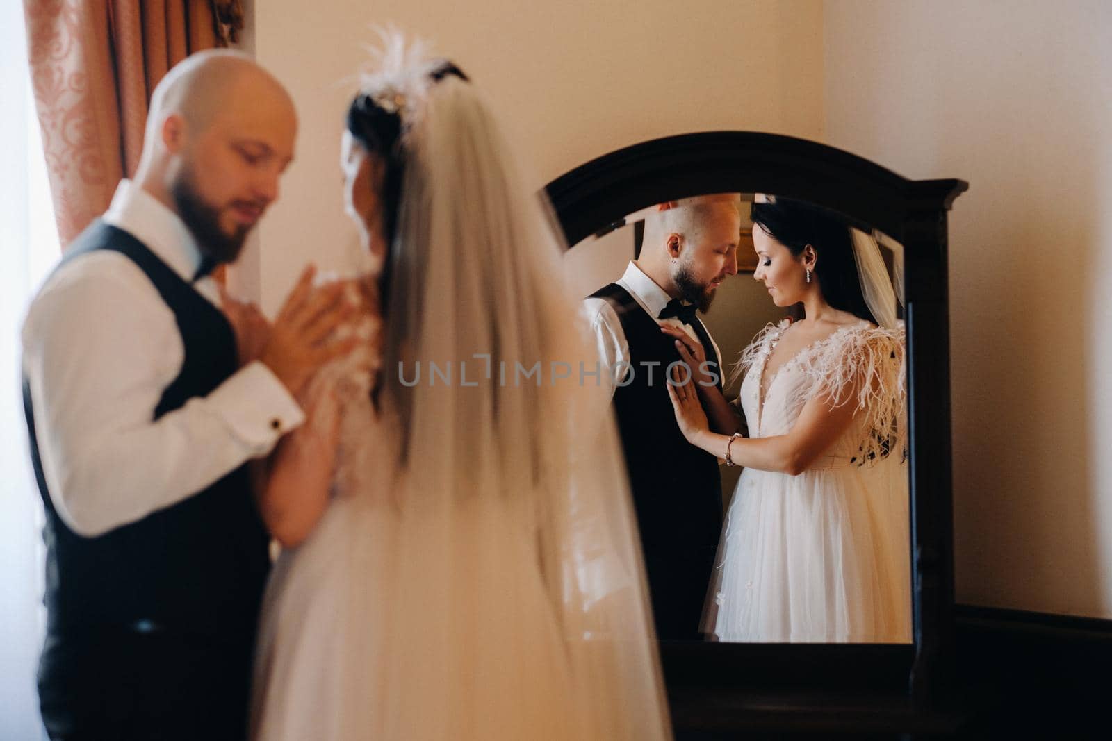 Morning of the bride. The groom stands with the bride near the mirror by Lobachad