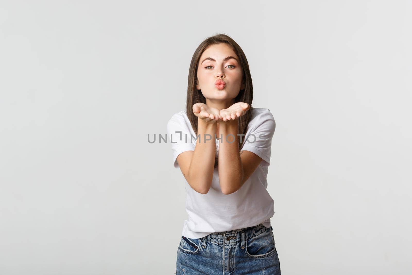 Tender attractive young woman blowing air kiss at camera flirty.