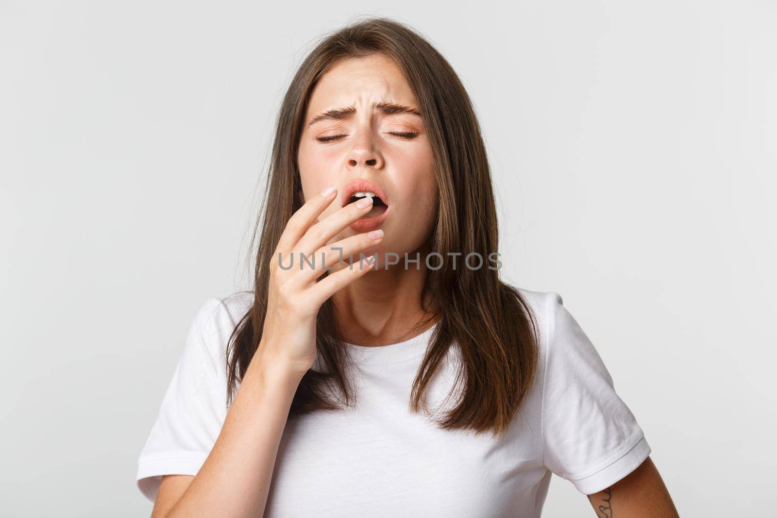 Portrait of girl with allergy sneezing, cover mouth with hand. Sick woman standing over white background.
