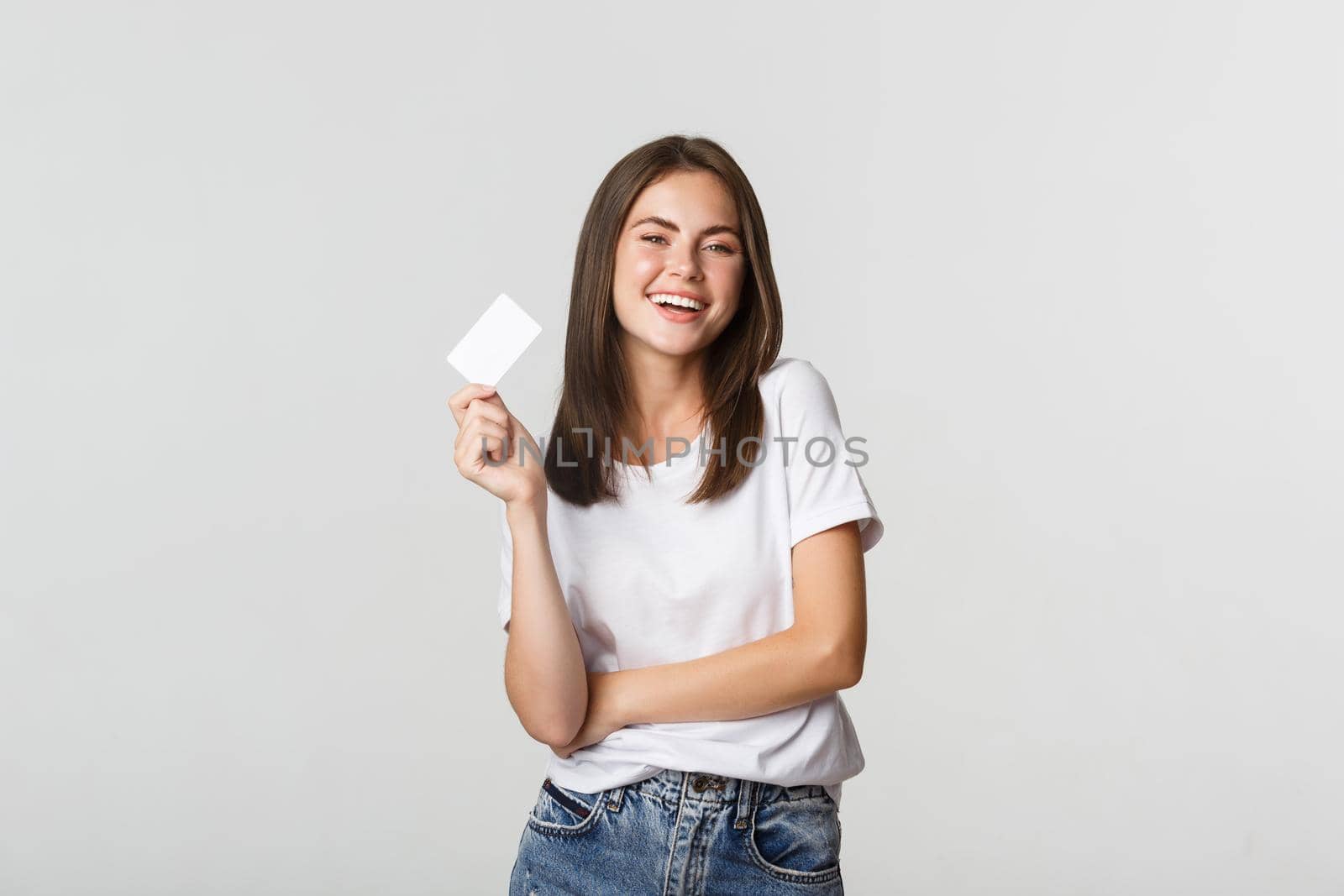 Attractive happy brunette girl laughing and holding credit card, white background.