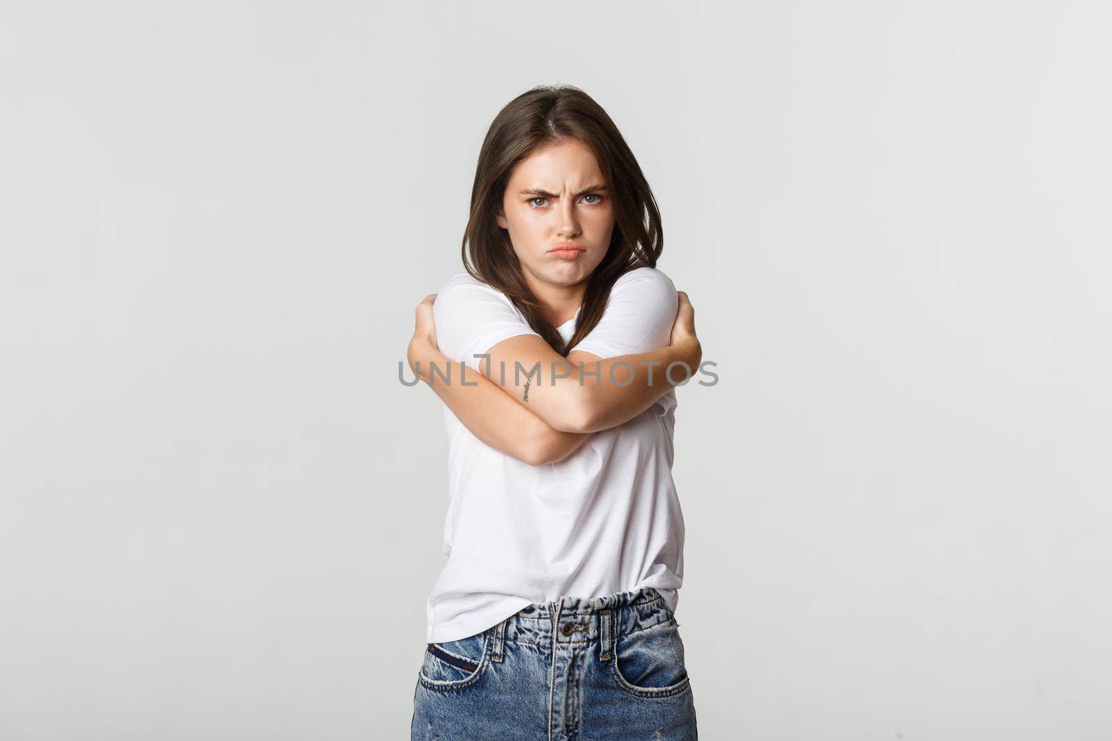 Offended sulking girl looking defensive and hugging herself.