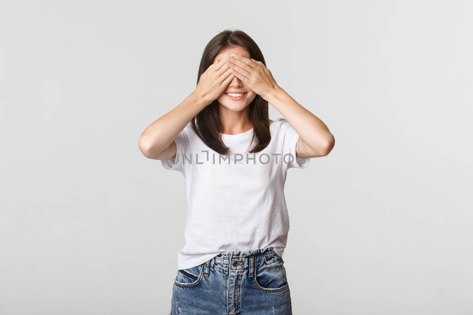 Dreamy beautiful girl smiling and waiting for surprise with shut eyes.