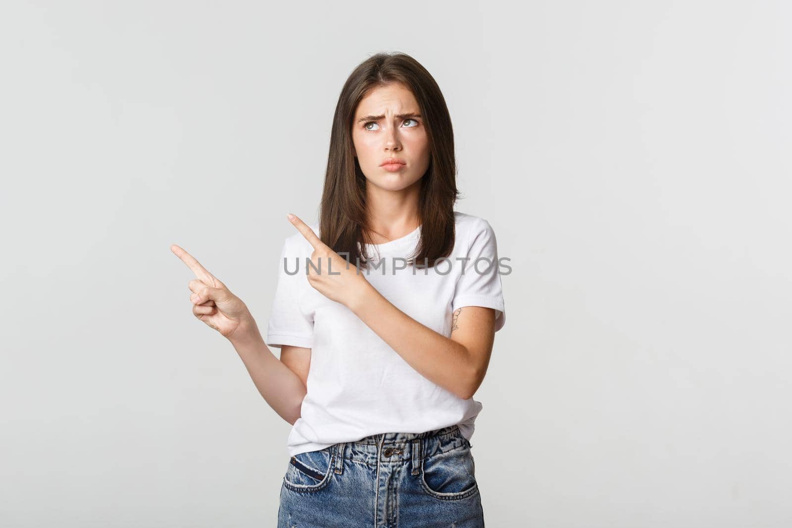 Upset cute girl pointing upper left corner, express regret.