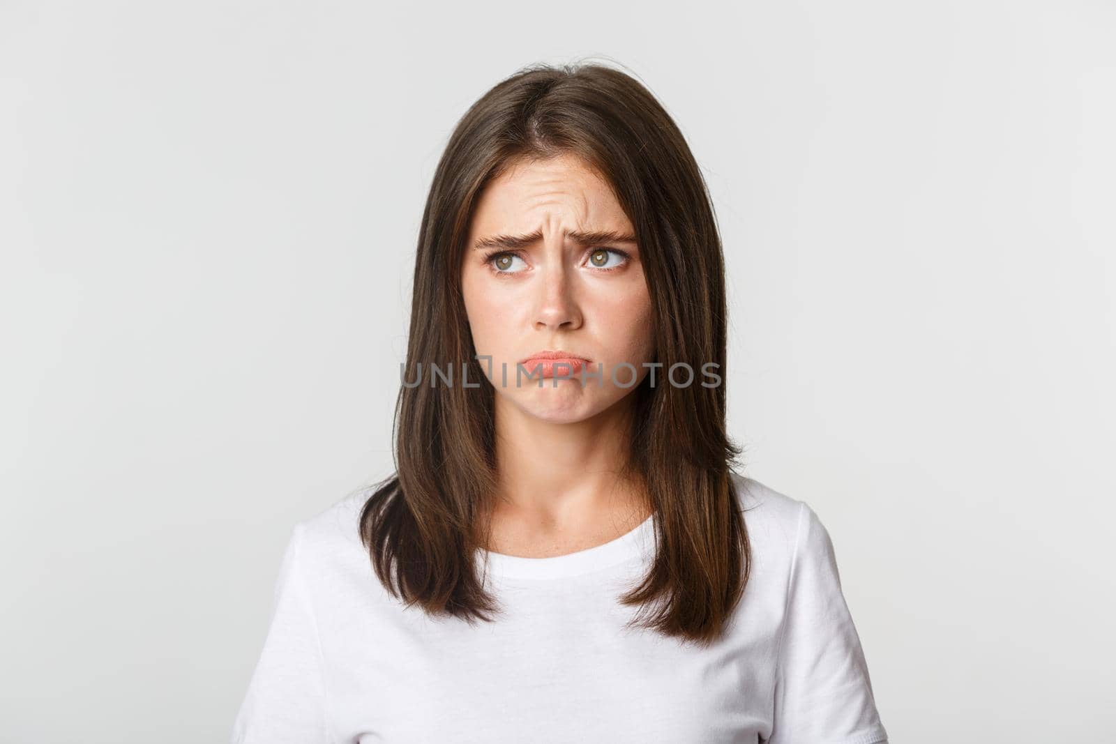 Close-up of sulking upset cute girl looking upper left corner with jealousy, standing sad over white background.