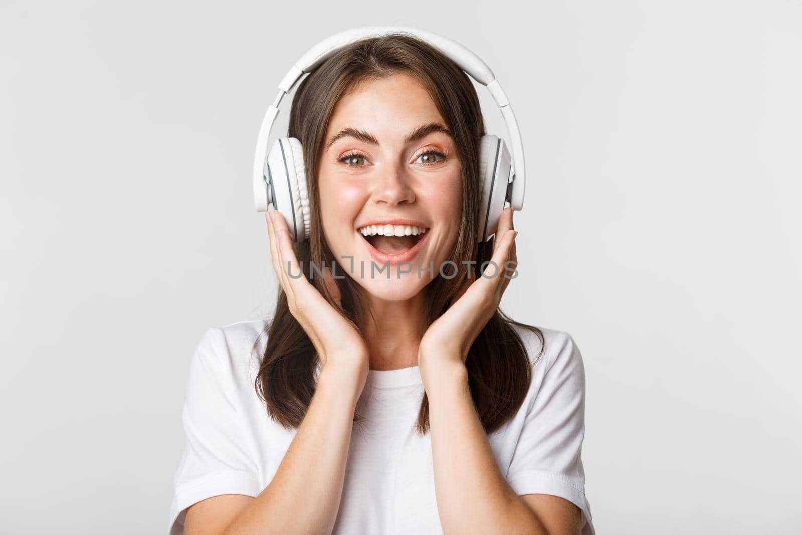 Close-up of smiling attractive brunette girl listening music in headphones, enjoying interesting podcast.