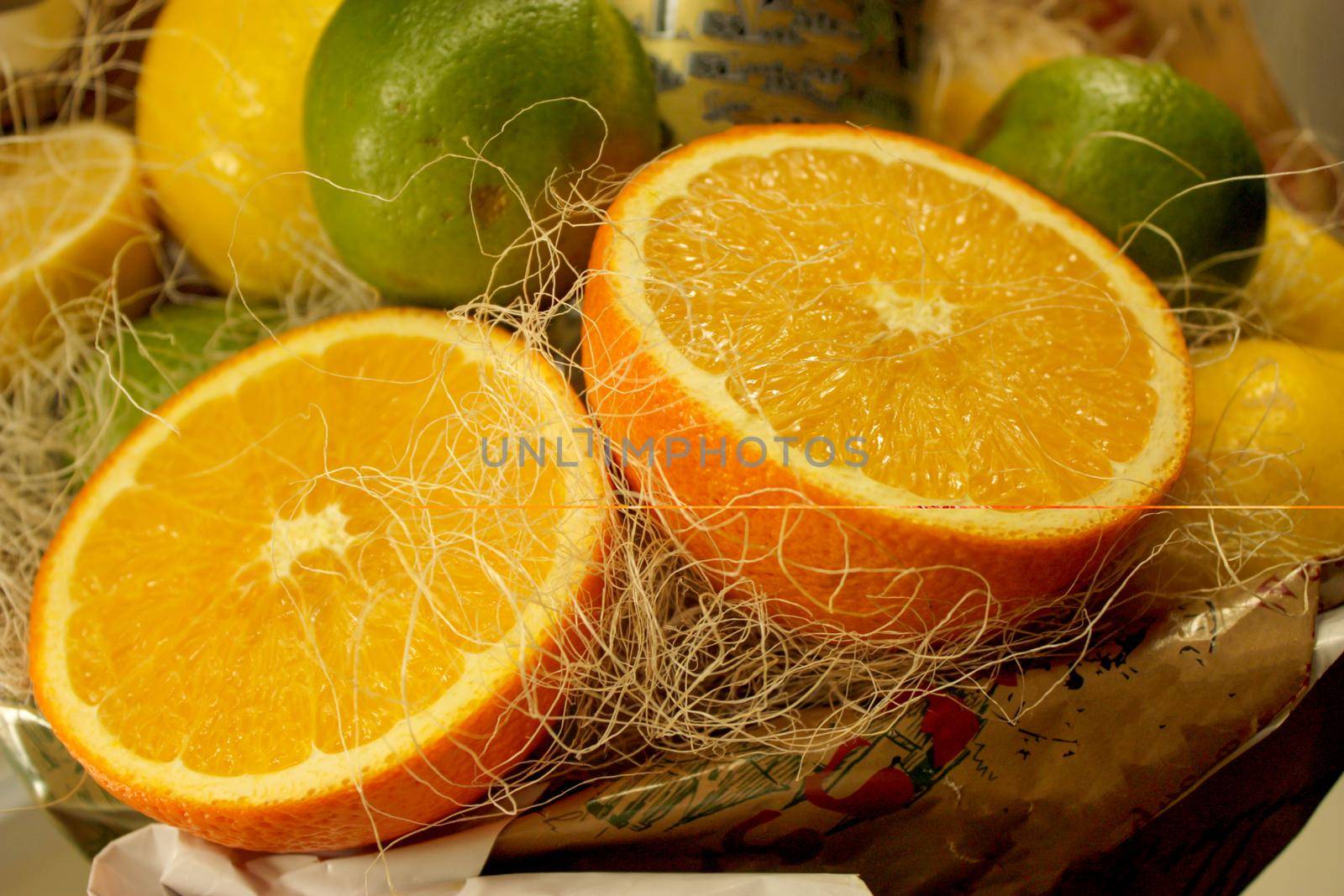 composition of two halves of oranges, two green limes and yellow lemons in the background. Close up photography