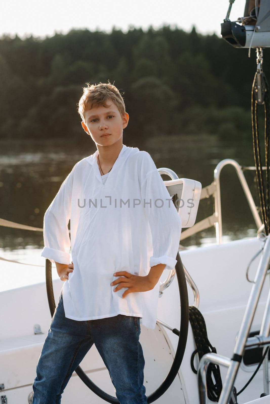 a little captain at the helm on a yacht. a little boy at the helm of the captain on a yacht at sunset.