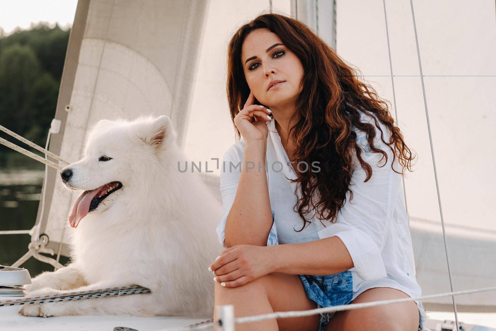 a happy woman with a big white dog on a white yacht in the sea.