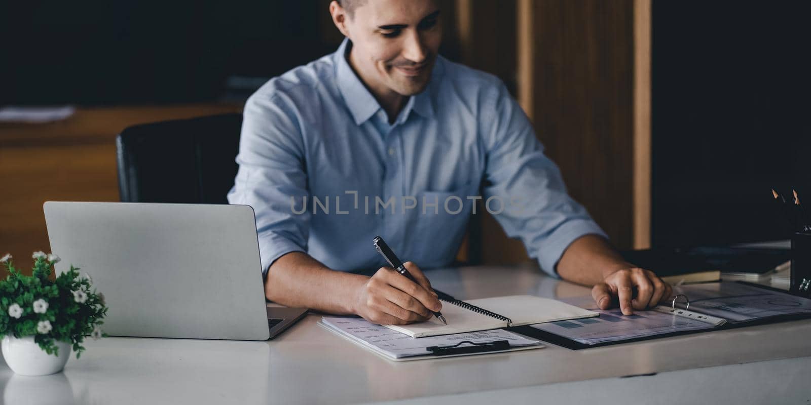 Close up hand of businessman with pen writing on notebook. male working for business financial analysis.