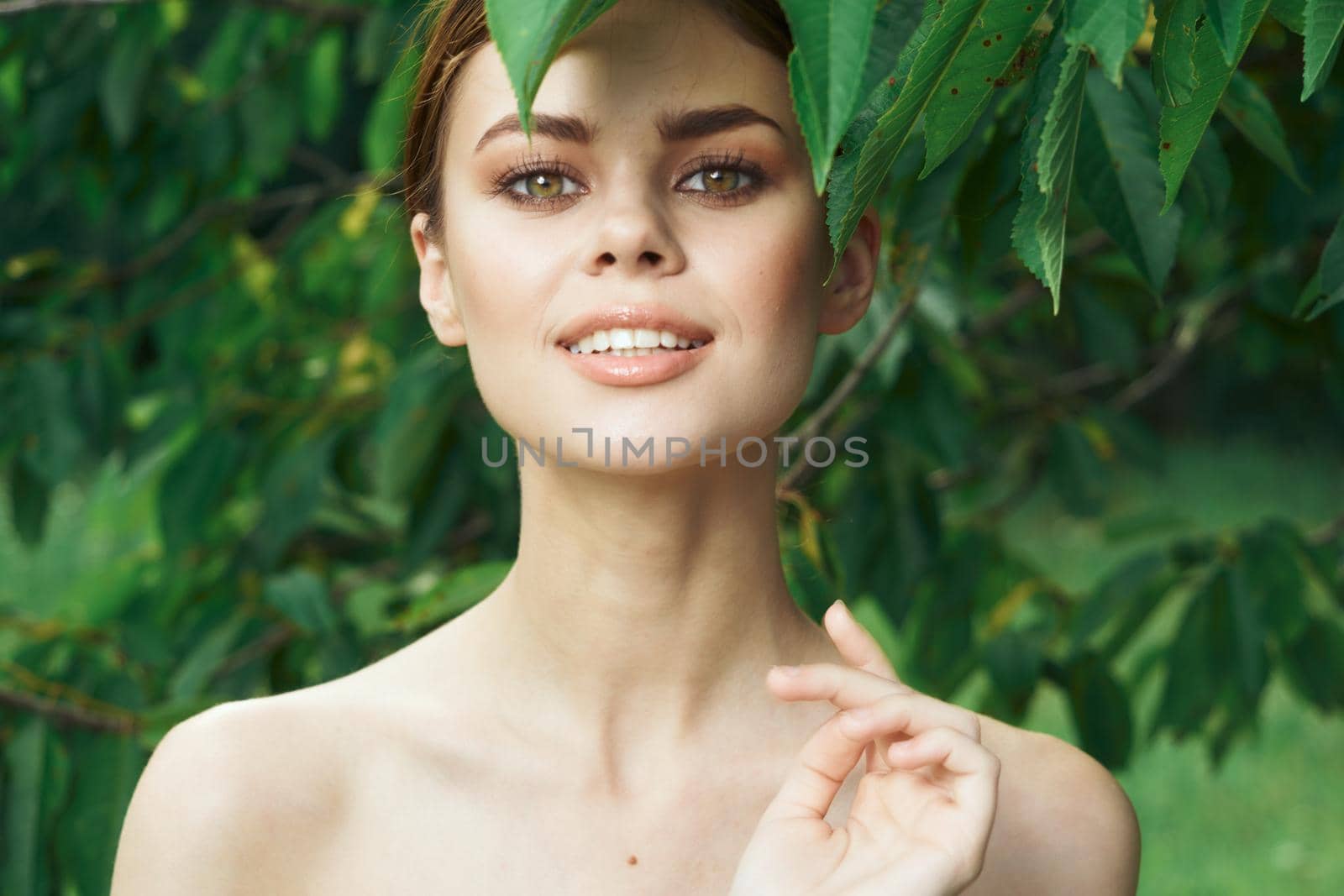smiling woman skin care bare shoulders green leaves nature cropped view. High quality photo