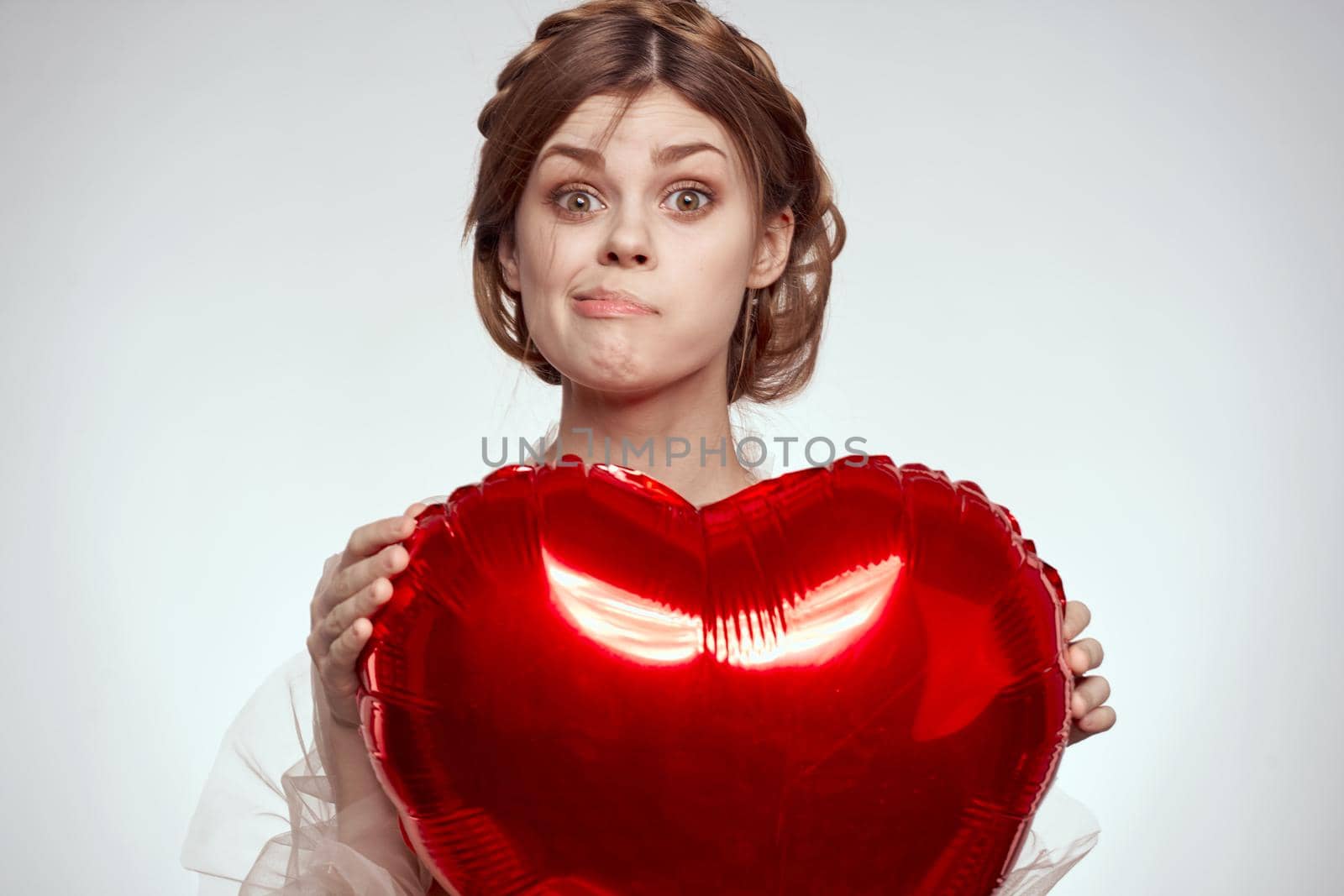 pretty woman red heart in the hands of the balloon light background. High quality photo