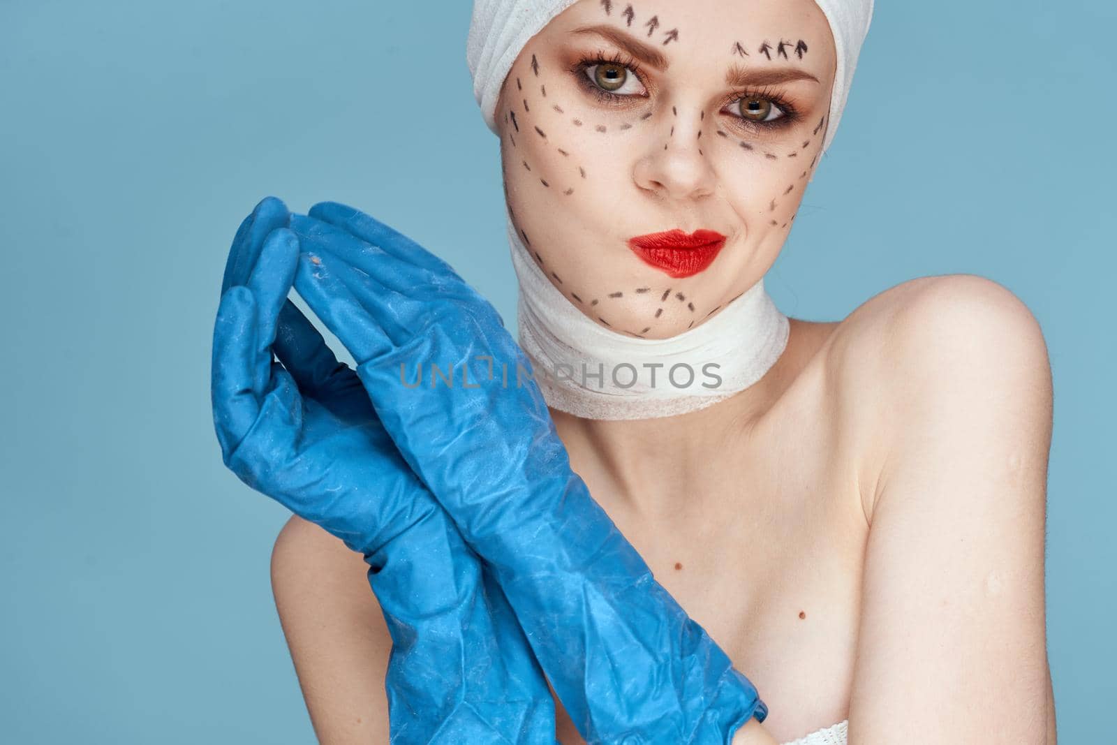 female patient posing in blue gloves red lips surgery facial rejuvenation studio lifestyle. High quality photo