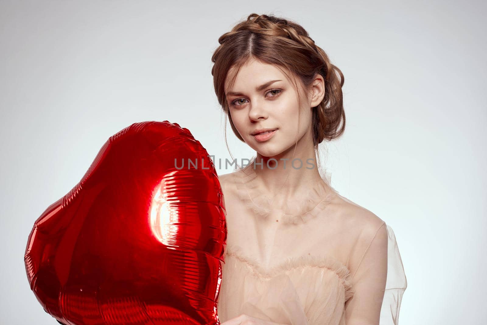 portrait of a woman red heart in the hands of the balloon light background. High quality photo