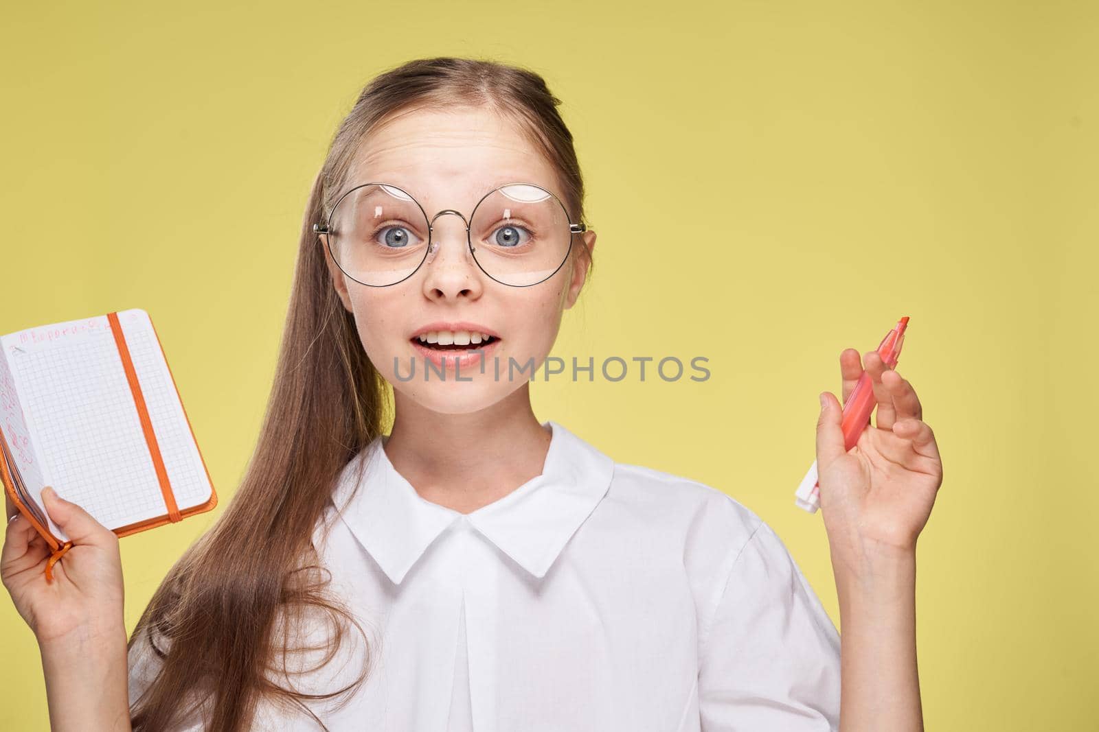 schoolgirl with textbook in hands learning childhood yellow background. High quality photo