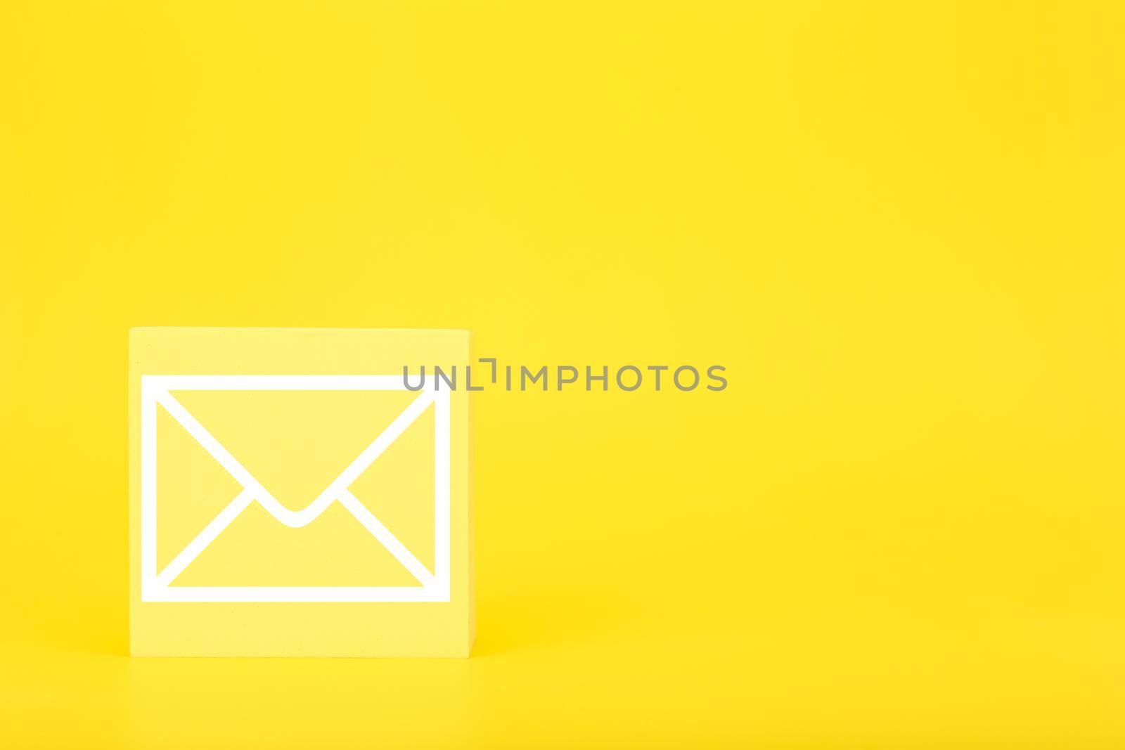 Email marketing or newsletter concept. Envelope drawn on toy square against bright yellow background with copy space by Senorina_Irina