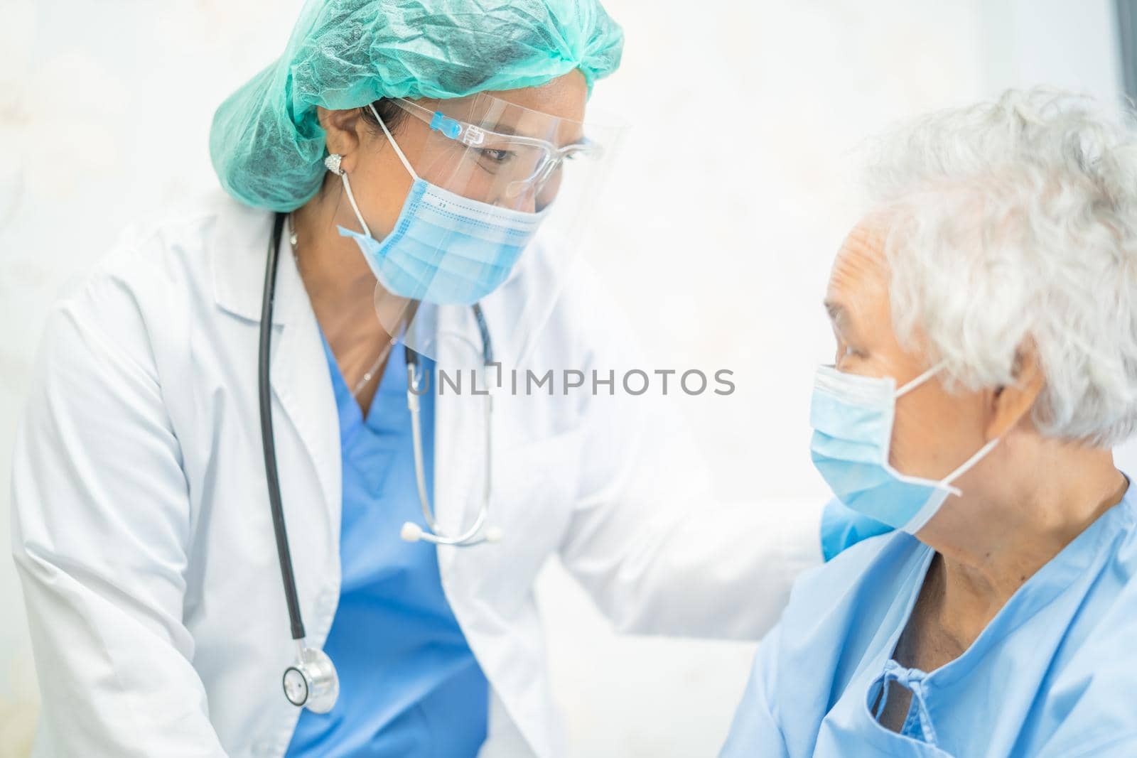 Asian doctor wearing face shield and PPE suit new normal to check patient protect safety infection Covid-19 Coronavirus outbreak at quarantine nursing hospital ward.