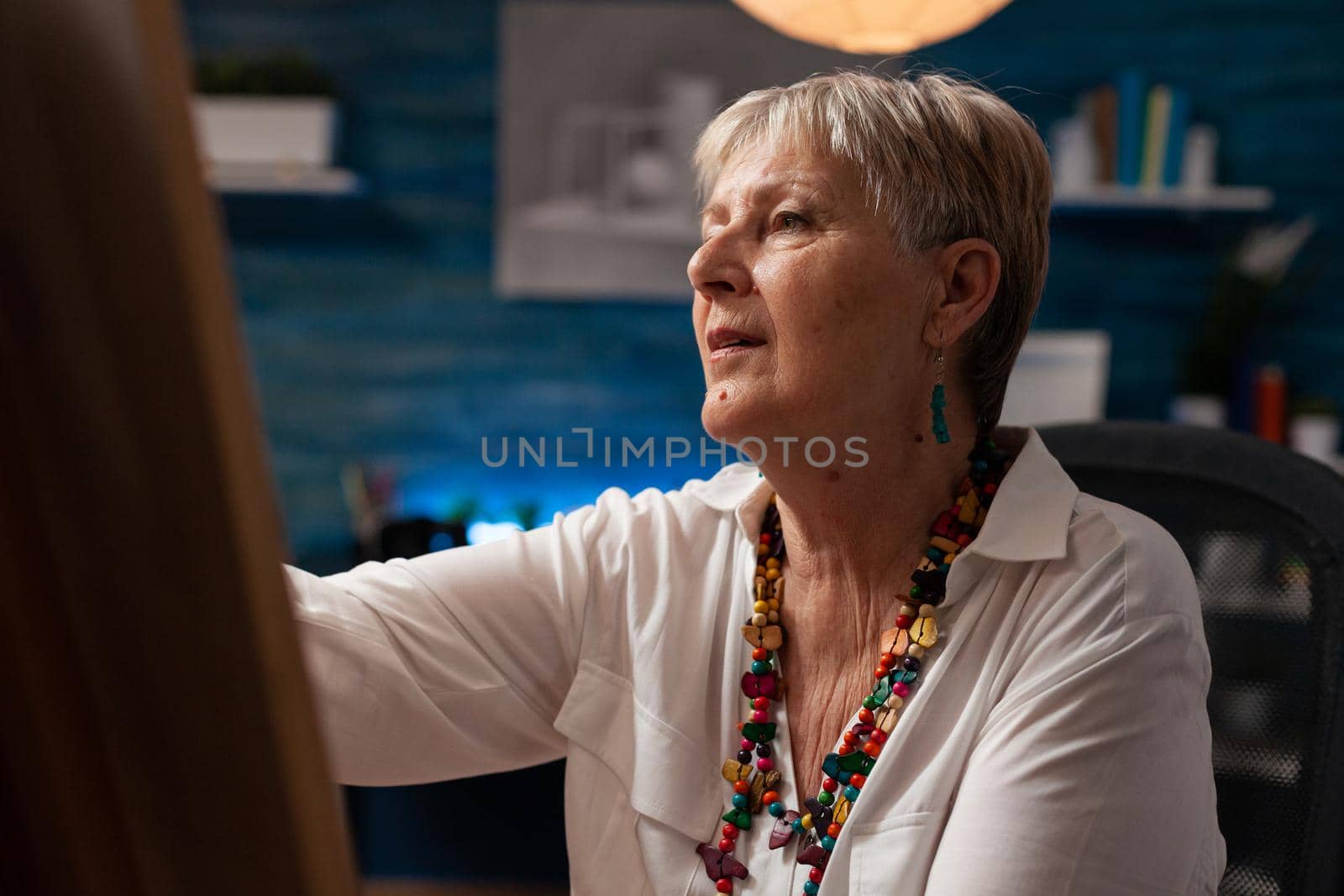 Close up of aged woman drawing on canvas with pencil while sitting in art studio space. Elder artist working on professional masterpiece design with artistic equipment and tools indoors