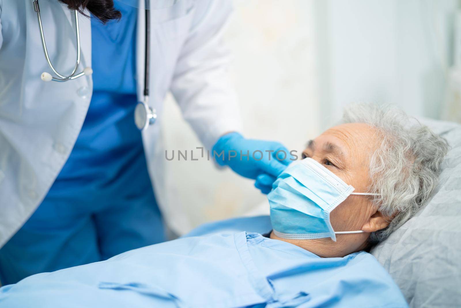 Doctor checking Asian senior or elderly old lady woman patient wearing a face mask in hospital for protect infection and kill Novel Coronavirus Covid-19 virus.