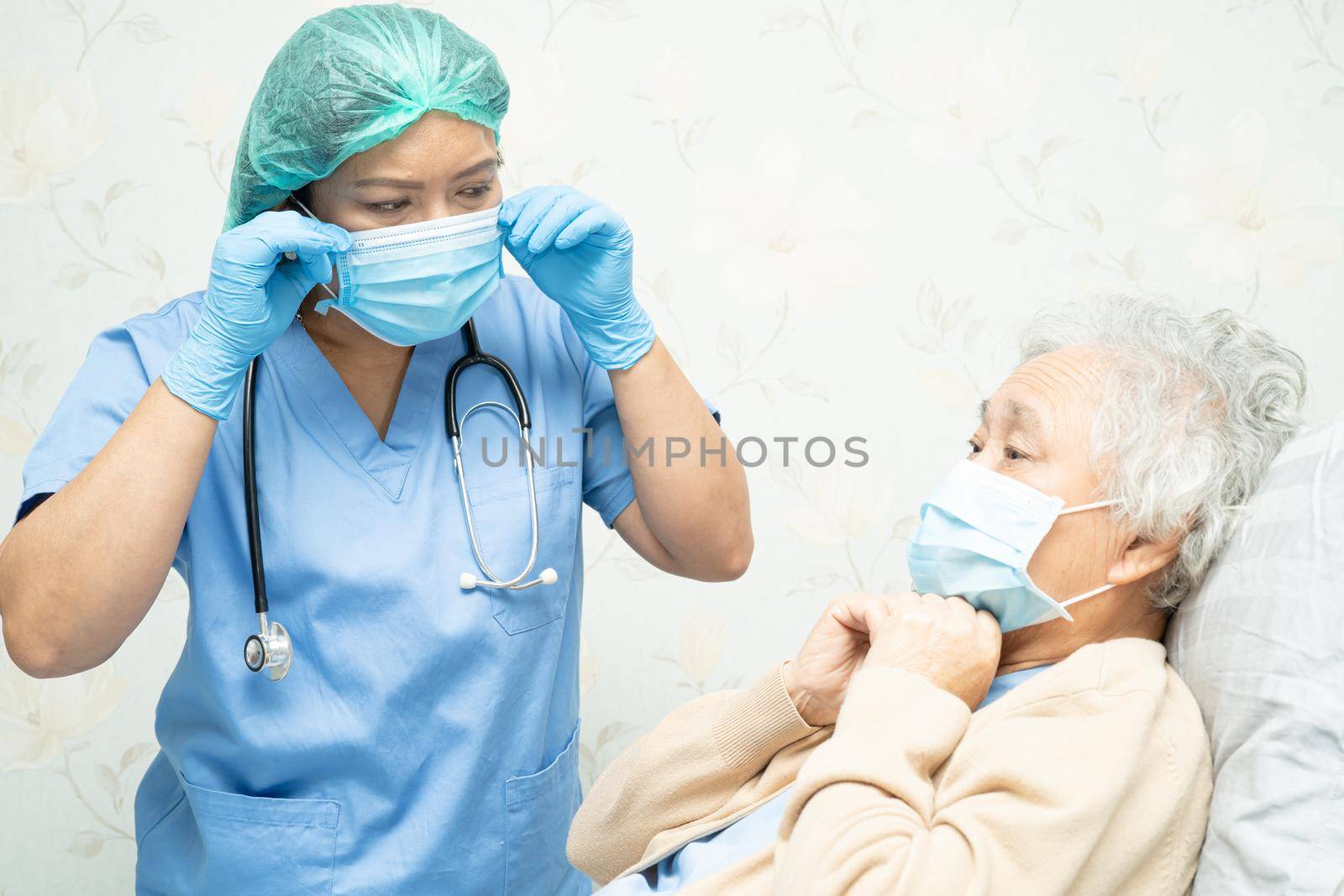 Doctor teching Asian senior woman patient wearing mask in hospital for protect Covid-19 Coronavirus.