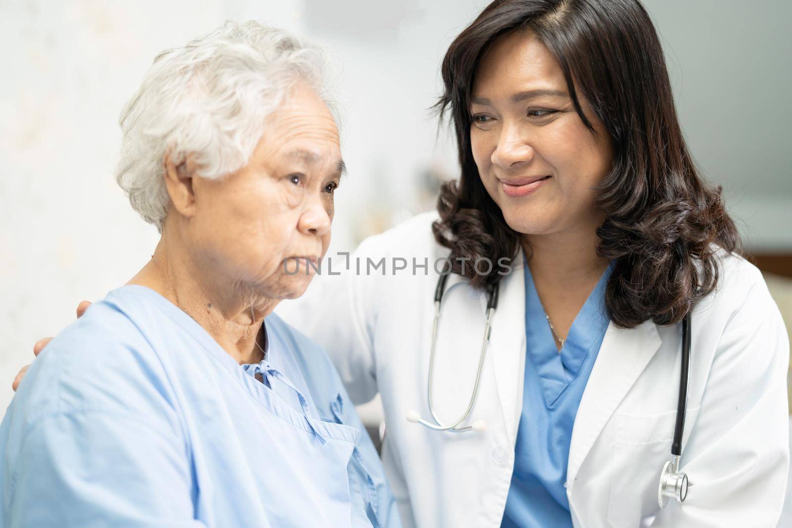 Doctor touching Asian senior or elderly old lady woman patient with love, care, encourage and empathy at nursing hospital ward, healthy strong medical concept
