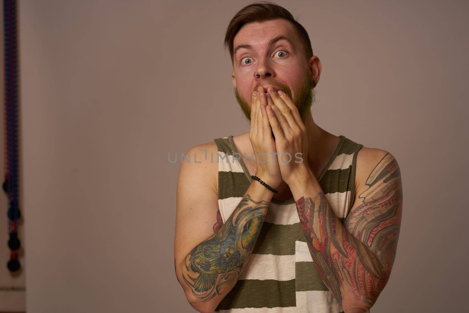 handsome man with tattoos on his arms fashionable hairstyle emotions. High quality photo