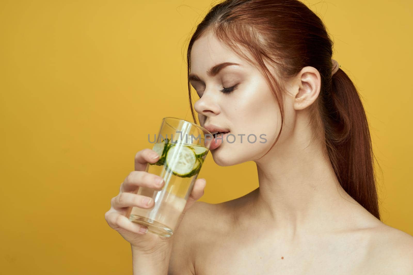 woman with cucumber drink vitamins body care yellow background. High quality photo
