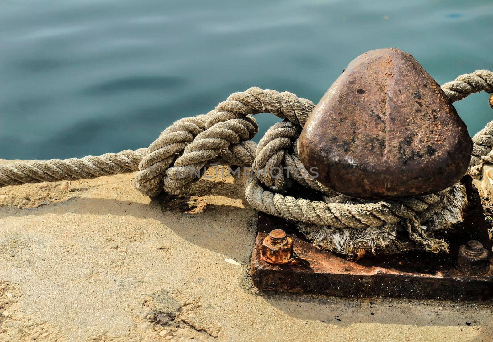 Rusty mooring bollard with tied rope in the port of Santa Pola, Alicante, Spain