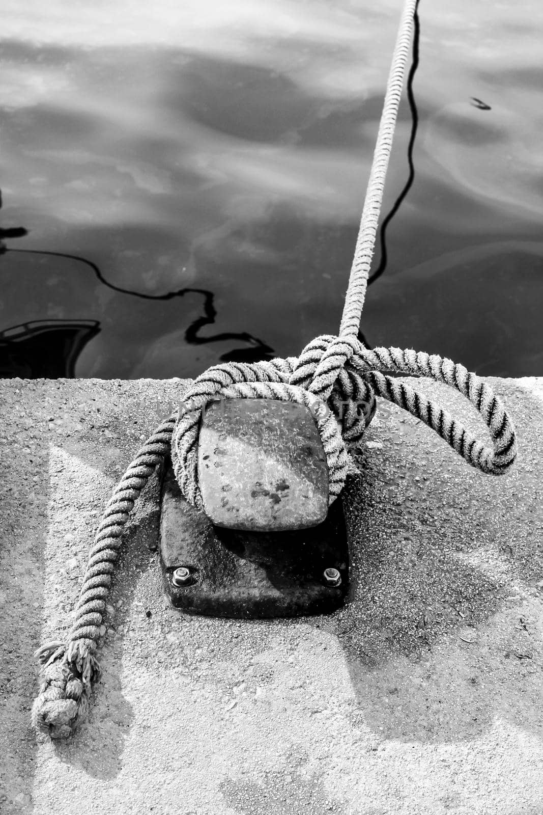 Rusty mooring bollard with tied rope in the port of Santa Pola, Alicante, Spain