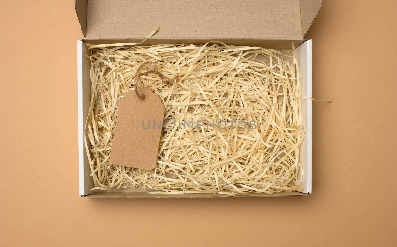 empty rectangular open corrugated paper box with sawdust inside. Packaging, containers for transportation on a brown background by ndanko