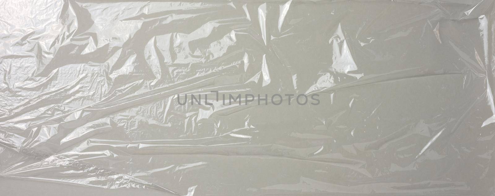 texture of crumpled transparent polyethylene on a gray background, full frame. Banner