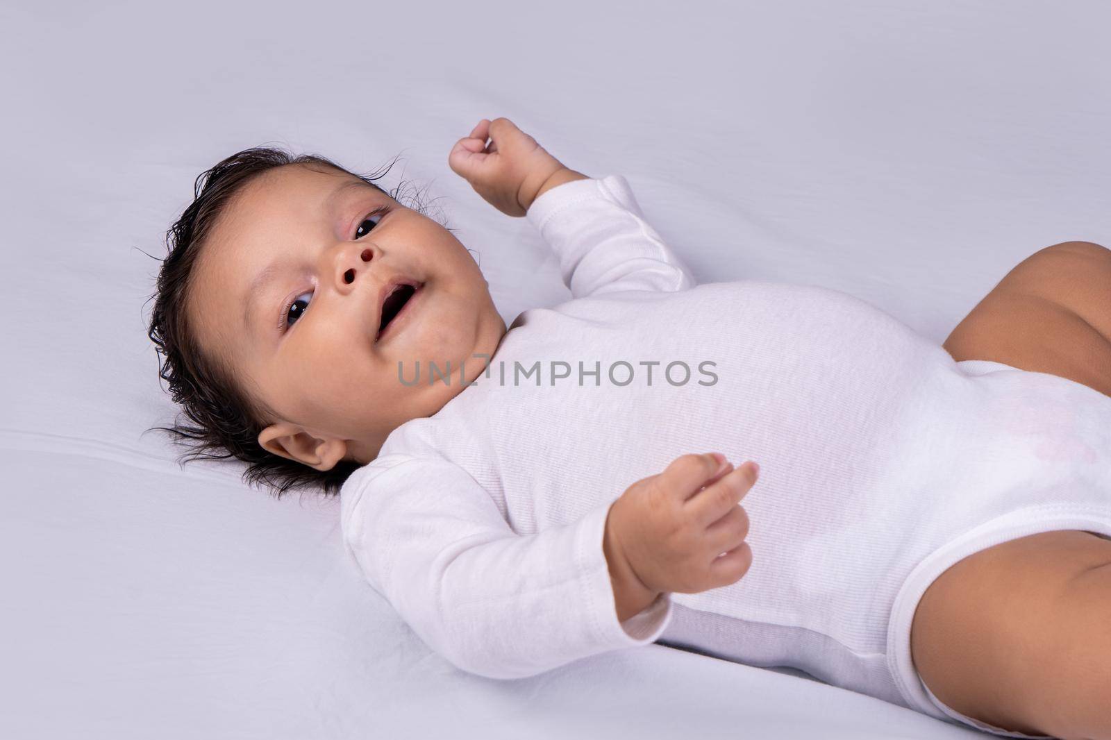 Infant lying on his back smiling and looking at the camera