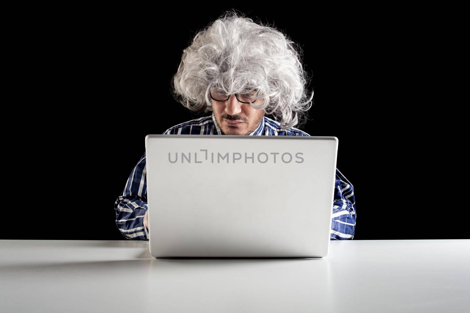 A boomer senior-focused concentrated sit at the desk looking at laptop computer by bepsimage