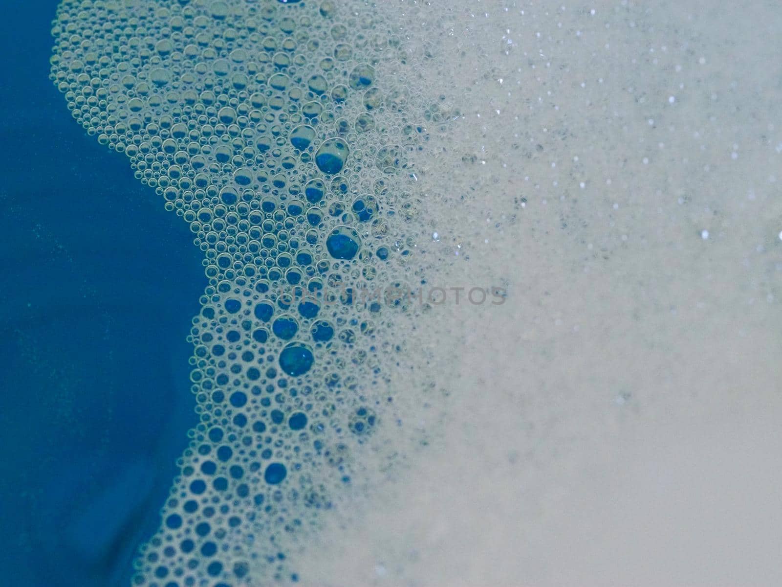 Close-up picture of their pattern in the bubbles of bath foam in blue water