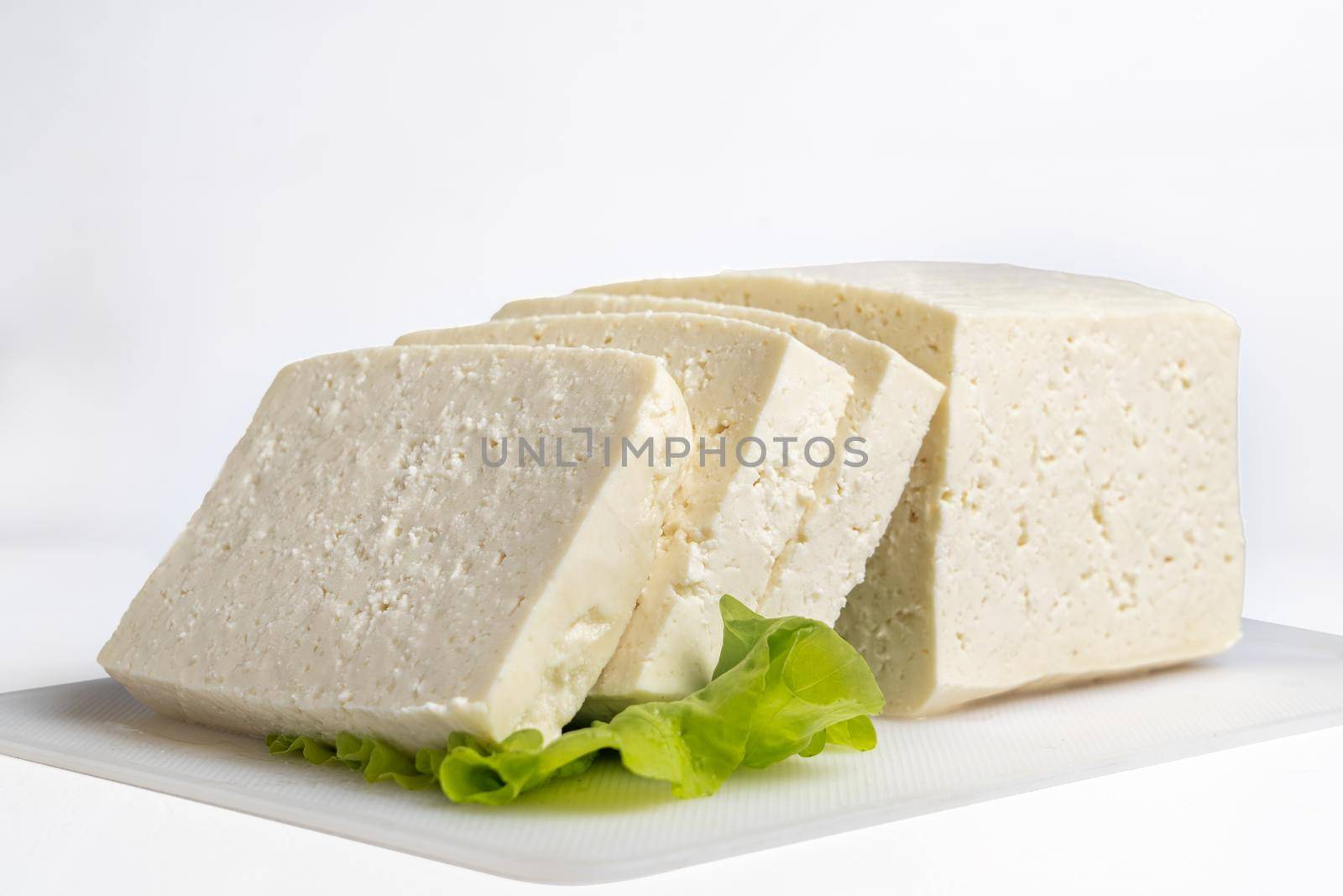 White cheese cut into several pieces on a white surfaceand white background