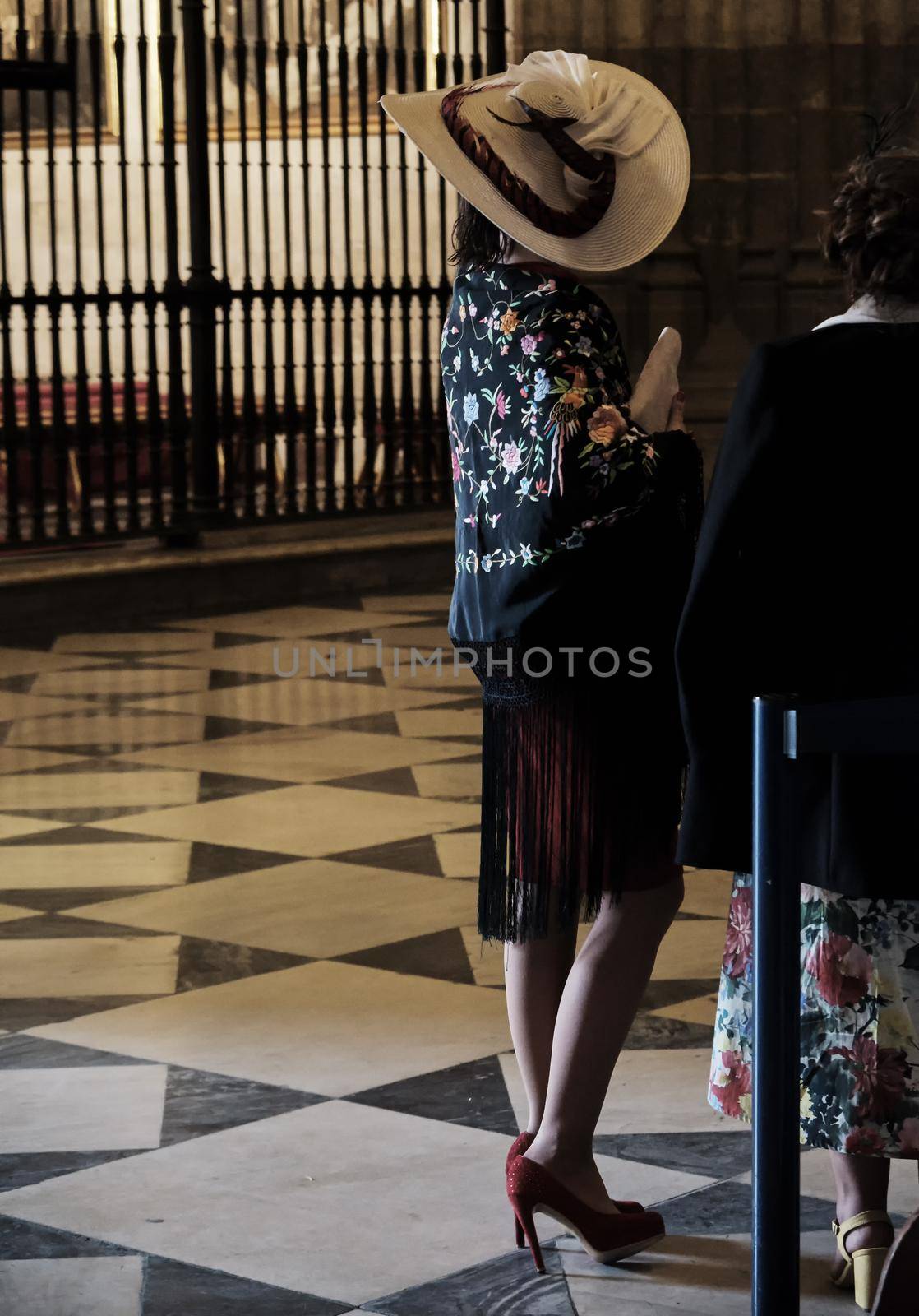 woman in the church wearing a traditional spanish flamenco andalusian dress for a wedding ceremony. by Sandronize