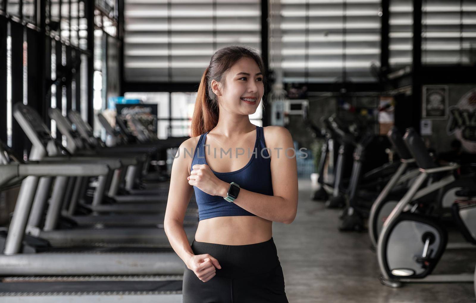 Portrait of confident beautiful asian fitness woman standing after exercise in gym. Concept of slim and healthy happy girl workout.