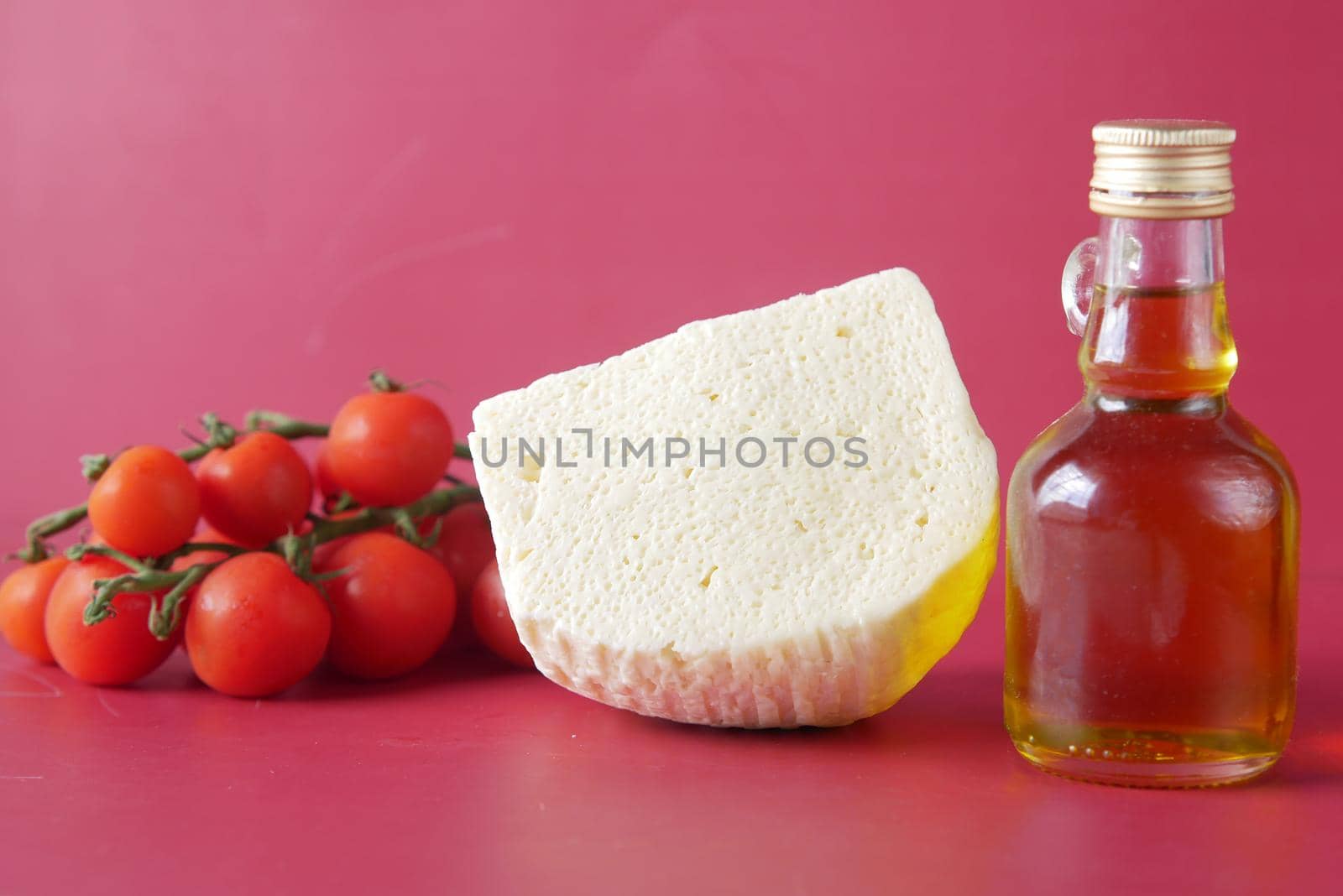 cherry tomato, cheese and olive oil on table .