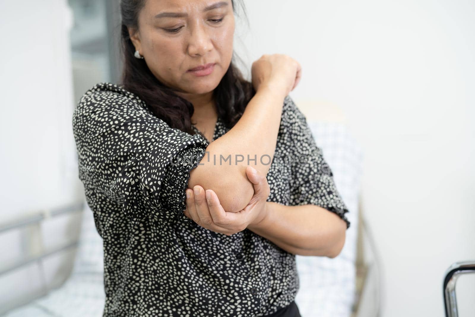 Asian middle-aged lady woman patient touch and feel pain her elbow and arm, healthy medical concept. by pamai